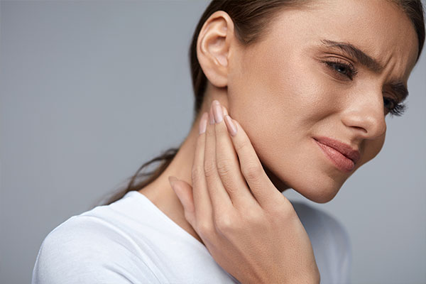 woman in pain rubbing at neck