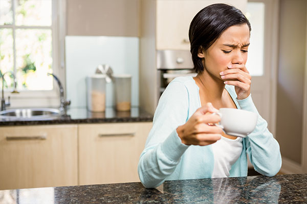 woman wincing drinking coffee needs root canals
