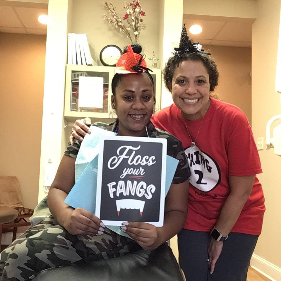 staff celebrating halloween with sign saying floss your fangs